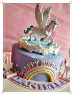 a birthday cake with a horse on top and rainbows around the edges, in front of a pink background