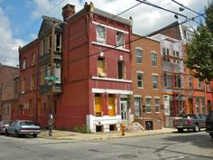 an old brick building on the corner of a street with cars parked in front of it