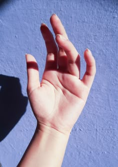 a person's hand reaching up towards the sky with their shadow on the wall