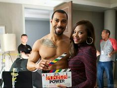 a shirtless man and woman holding a clapper in a room with other people