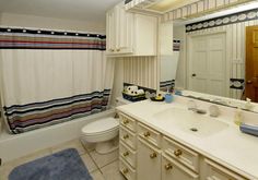 a bathroom with a sink, toilet and bathtub covered in striped shower curtaines