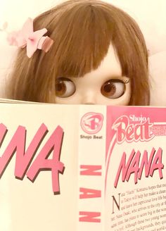 a doll is reading a book with her eyes wide open and brown hair in front of her face