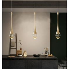 three lights hanging from the ceiling above a counter in a room with black walls and flooring