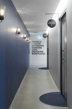 a long hallway with blue walls and lights on either side of the corridor is lit by two wall sconces