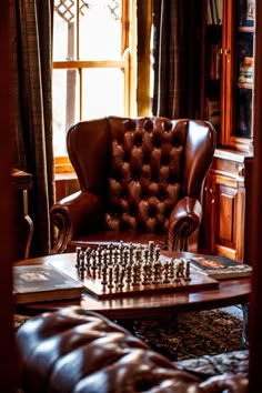 a chess board sitting on top of a wooden table in front of a leather chair