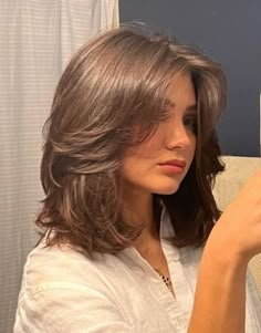 a woman is brushing her hair in front of a mirror with an electric toothbrush