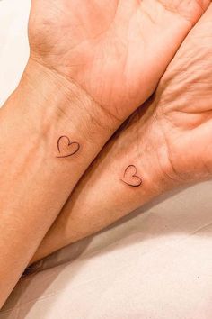 two hands holding each other with small hearts on their wrist tattoo designs for women and men