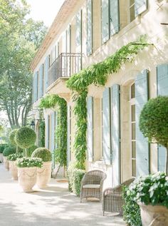 an outdoor patio with potted plants and wicker chairs on the side of it