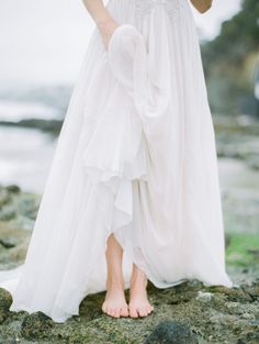 a woman in a white dress standing on rocks