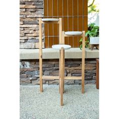 two wooden chairs sitting next to each other in front of a stone wall and planter