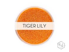 the words tiger lily written on top of an orange glitter powder in a white bowl