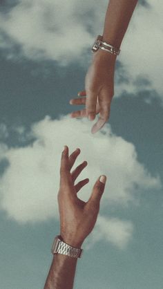 two hands reaching for each other in the air with clouds behind them and blue sky above