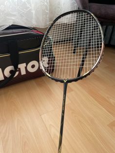 a close up of a tennis racquet on a wooden floor near a bag