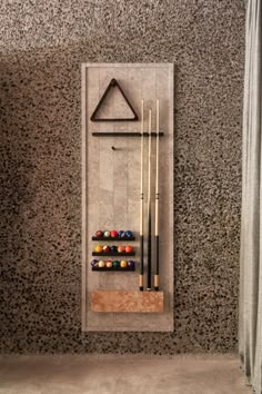 a rack with pool balls and cues in front of a wall mounted coat rack