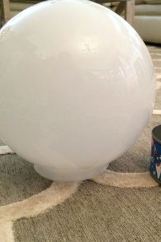 a large white balloon sitting on top of a rug next to a can of paint