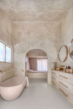 a bathroom with a large tub and two sinks in it's center area, along with mirrors on the wall