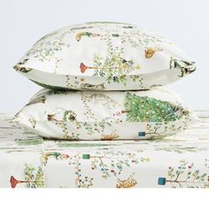 three pillows stacked on top of each other in front of a white background with trees and birds