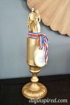 a gold trophy with an olympic decoration on top