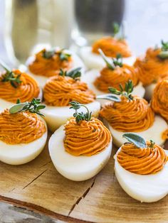 deviled eggs with garnishes are arranged on a cutting board, ready to be eaten