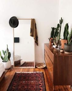 a room with wooden floors and plants on the wall, along with a large mirror