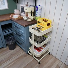 a kitchen with blue cabinets and wooden flooring next to a counter top filled with dishes