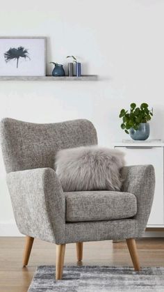 a chair with a fur pillow on top of it in front of a white wall