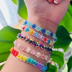 a woman's hand holding several different colored bracelets on her left and right arm