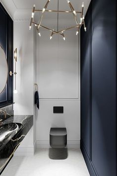 a bathroom with black and white walls, marble counter tops and a gold chandelier hanging from the ceiling