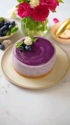 a cake with blueberries and flowers in a vase next to it on a plate