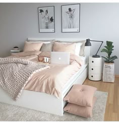 a white bed sitting in a bedroom next to a laptop computer