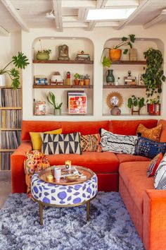 a living room filled with furniture and lots of plants on the wall above it's shelves