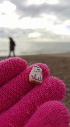 a close up of a person wearing pink mittens with a sticker on it