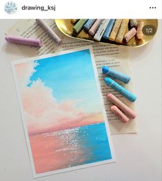 pastel crayons are sitting on top of an open book next to some watercolor pencils