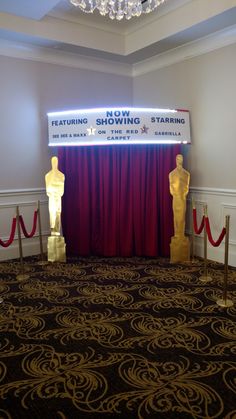 the stage is set up for an event with red curtains and gold statues on it