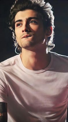 a man with long hair and tattoos on his arm, wearing a white t - shirt