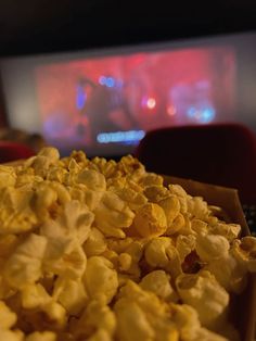 a box filled with popcorn sitting on top of a table in front of a tv