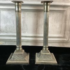 two silver candlesticks sitting on top of a black table