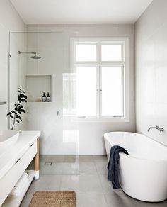 a white bathroom with a large tub and sink