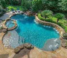 an aerial view of a swimming pool surrounded by lush green trees and bushes, with lounge chairs around it