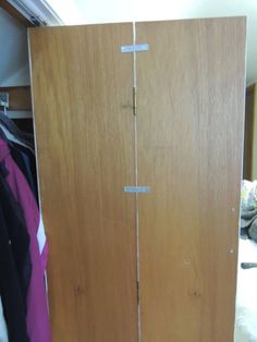 a wooden closet with clothes hanging on it