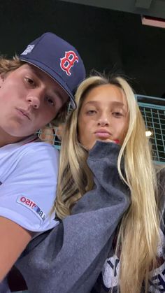 two young people posing for a photo in front of a baseball dugout with their arms around each other