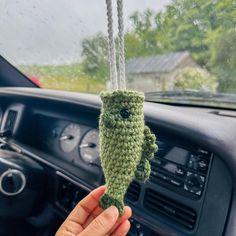 a person holding up a crocheted stuffed animal in the dashboard of a car