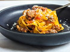 a black bowl filled with pasta and meat