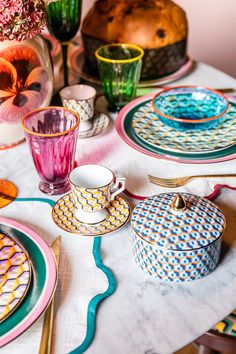 the table is set with colorful dishes and cups