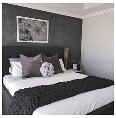 a bed with black and white blankets on it in a bedroom next to a painting