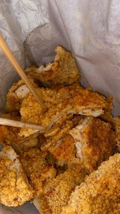 some food in a basket with chopsticks sticking out of the meat and vegetables