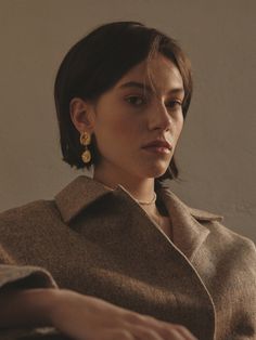 a woman sitting on a couch wearing earrings