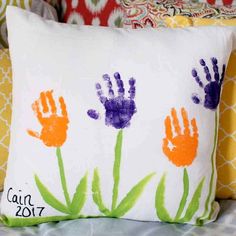 a pillow with handprints on it sitting on a couch in front of pillows