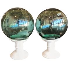 two glass balls sitting on top of white pedestals