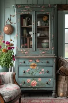 an old china cabinet with flowers painted on the doors and drawers, in a living room